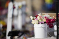 Buckets of flowers sit near the crosses for the victims at a makeshift memorial for a mass shooting over the weekend at a gay nightclub Wednesday, Nov. 23, 2022, in Colorado Springs, Colo. (AP Photo/David Zalubowski)