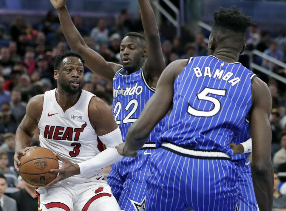 Miami Heat's Dwyane Wade (3) looks to pass the ball as he gets between Orlando Magic's Jerian Grant (22) and Mo Bamba (5) during the first half of an NBA basketball game, Sunday, Dec. 23, 2018, in Orlando, Fla. (AP Photo/John Raoux)