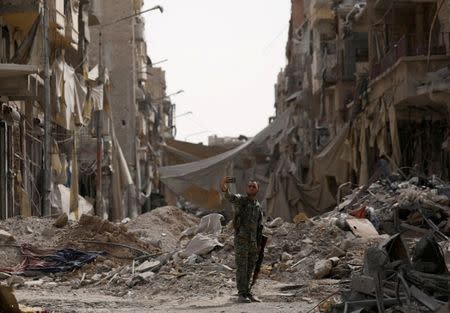 A fighter from the Syrian Democratic Forces takes a selfie as he stands near rubble at a damaged site in Raqqa. REUTERS/Rodi Said