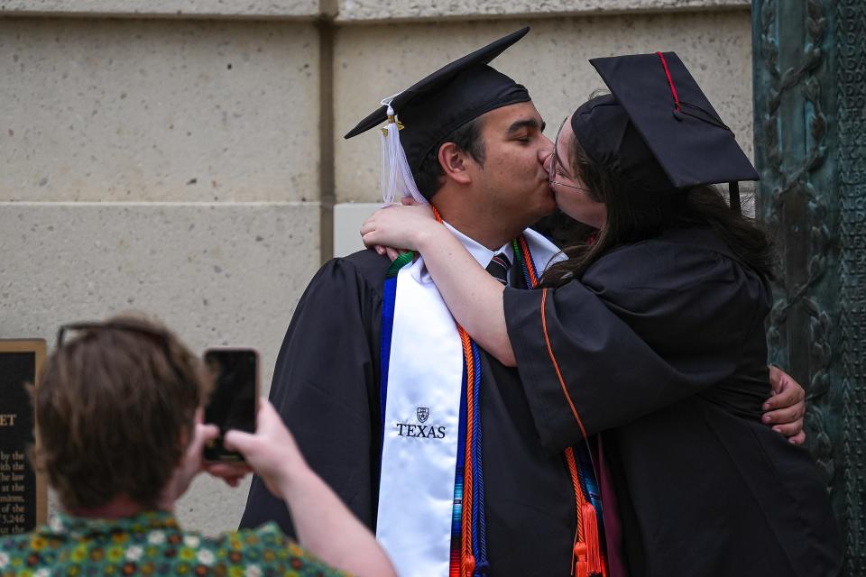 Anna Kaminetz, a design and communication graduate, kisses Diego Collazo, a Plan II government and history graduate, ahead of Saturday night's commencement ceremony at Royal-Memorial Stadium.