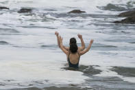 A couple react as they take a mid-winter swim at Bronte Beach as rain continues to fall in Sydney, Australia, Wednesday, July 6, 2022. More than 50,000 residents of Sydney and its surrounds have been told to evacuate or prepare to abandon their homes on Tuesday as Australia's largest city braces for what could be its worst flooding in 18 months. (AP Photo/Mark Baker)