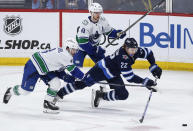 Winnipeg Jets' Mason Appleton (22) reaches out for the pass as Vancouver Canucks' Conor Garland (8) and Elias Pettersson (40) defend during the third period of an NHL hockey game Thursday, April 18, 2024, in Winnipeg, Manitoba. (John Woods/The Canadian Press via AP)