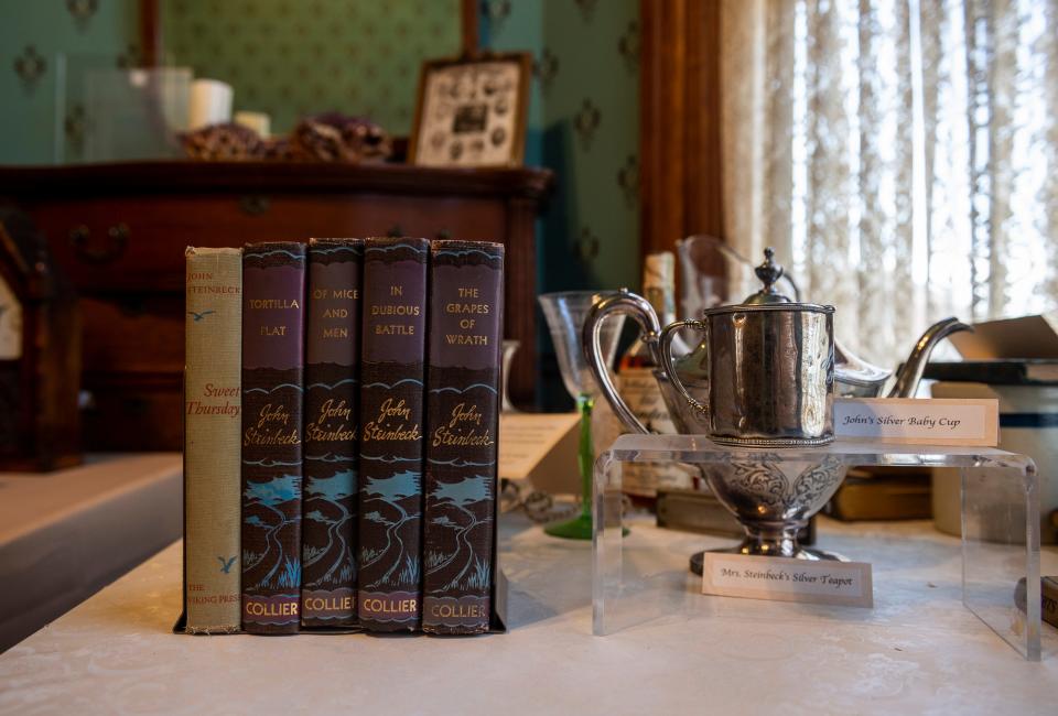 Five copies of John Steinbeck's books are placed next to Steinbeck's silver baby cup inside The Steinbeck House in Salinas, Calif., on Wednesday, March 24, 2021. 