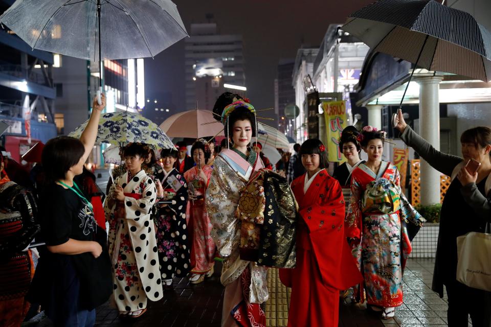 Japanese people wearing traditional clothes walk in the street after attending a kimono fashion show in Oita, Japan, Oct. 18, 2019.