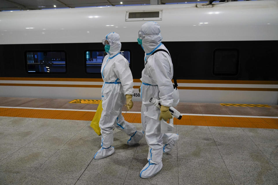 Two workers in protective gear walk way from a train car designated for Olympic workers after disinfecting it at a train station ahead of the 2022 Winter Olympics, Thursday, Jan. 27, 2022, in Zhangjiakou, China. (AP Photo/Jae C. Hong)