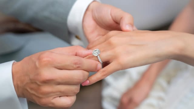 A man putting an engagement ring on a woman.