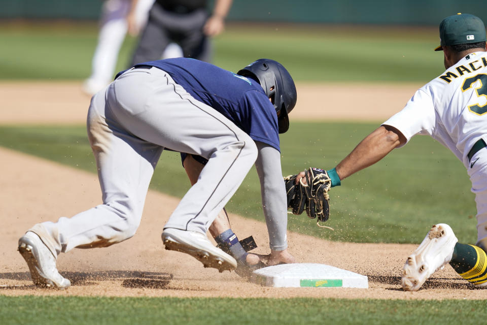 Seattle Mariners' Sam Haggerty, left, steals third base against Oakland Athletics third baseman Vimael Machín during the eighth inning of a baseball game in Oakland, Calif., Sunday, Aug. 21, 2022. (AP Photo/Godofredo A. Vásquez)
