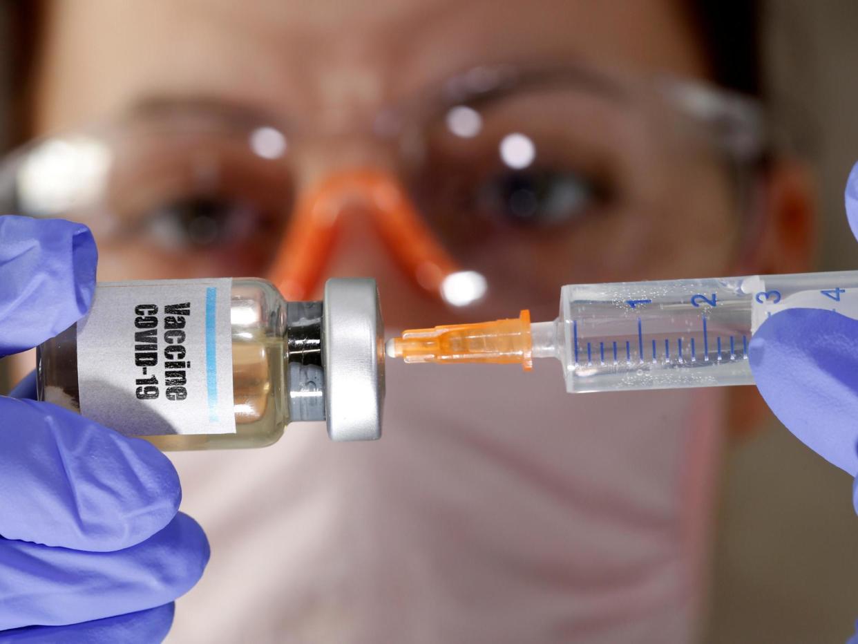 A woman holds a small bottle labelled with a "Vaccine Covid-19" sticker and a medical syringe in this illustration: (Reuters)