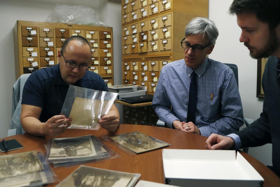 In this Thursday, Nov. 14, 2019 photo, Eric Hemenway, left, the director of archives and records for the Little Traverse Bay Band of Odawa Indians looks over photographs with University of Michigan William Clements Library Curator of Graphics, Clayton Lewis, center, and cataloger Jakob Dobb in Ann Arbor, Mich. The photographic collection was acquired by the library in 2016 from Richard Pohrt Jr. and represents some 80 indigenous groups. (AP Photo/Carlos Osorio)