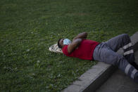 A man wearing a face mask to prevent the spread of coronavirus sleeps in a public park in Barcelona, Spain, Tuesday, Sept. 15, 2020. Spain's official death toll for the new coronavirus on Tuesday surpassed 30,000 fatalities as the country's caseload also increased beyond 600,000, becoming the first European country to overcome that threshold. (AP Photo/Emilio Morenatti)