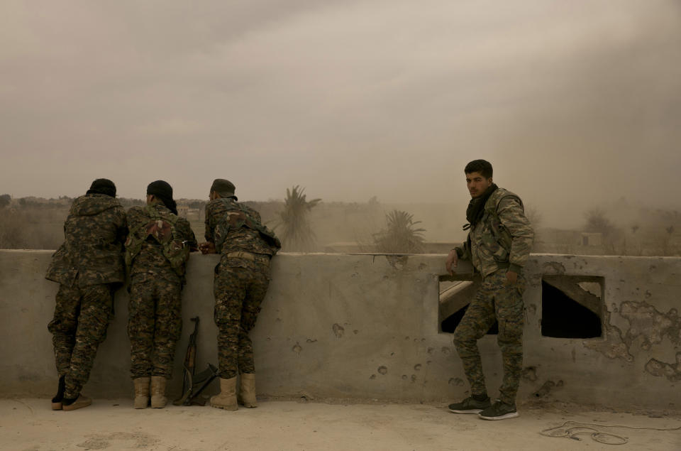 U.S.-backed Syrian Democratic Forces (SDF) soldiers watch from a rooftop the battle to oust Islamic State militants from Baghouz, Syria, Wednesday, March 13, 2019. (AP Photo/Maya Alleruzzo)