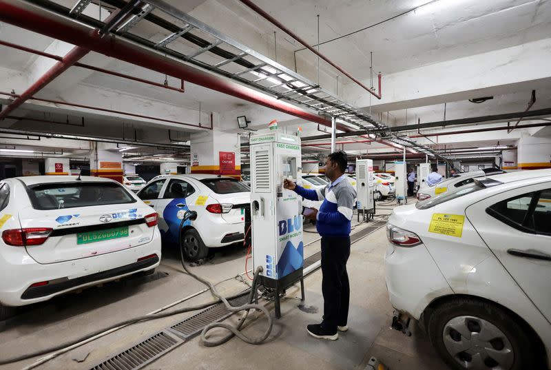 FILE PHOTO: A man charges an electric vehicle (EV) at the charging hub of Indian ride-hailing BluSmart Electric Mobility in Gurugram