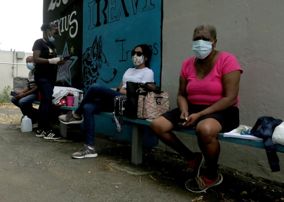 Electoral officials wait for ballots to arrive at a voting center in Carolina, Puerto Rico, Sunday, Aug. 9, 2020. Puerto Rico's primaries were marred by a lack of ballots in a majority of centers across the U.S. territory, forcing frustrated voters who braved a spike in COVID-19 cases to turn around and go back home. (AP Photo/Danica Coto)