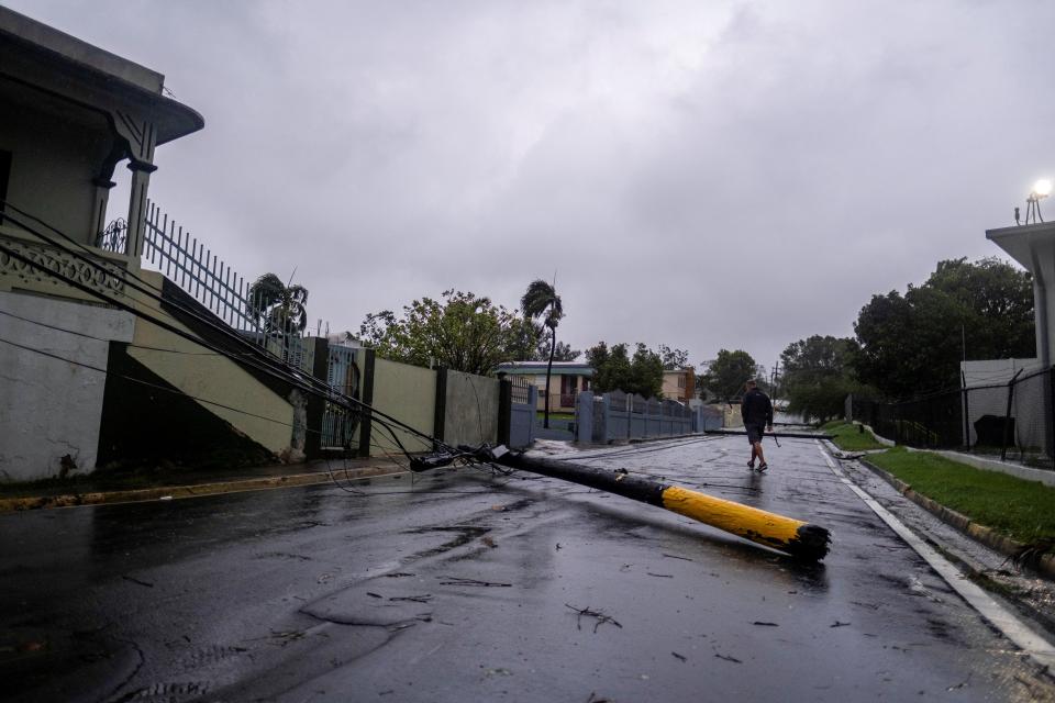 A man walk past an electricity pole that was damaged by Hurricane Fiona in Yauco, Puerto Rico, 18 September 2022 (Reuters)