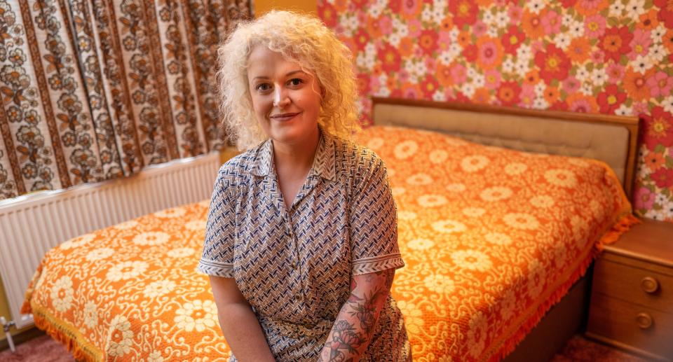 Simone Radley sits in her bedroom which is decorated with 1970s wallpaper and a retro duvet. (SWNS)