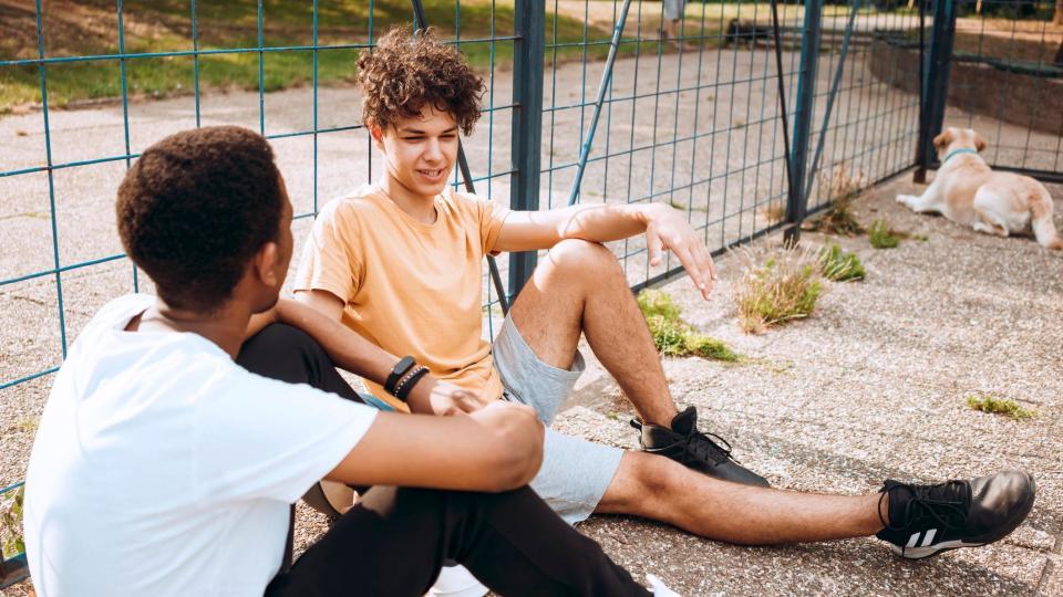 dos adolescentes conversan sentados 