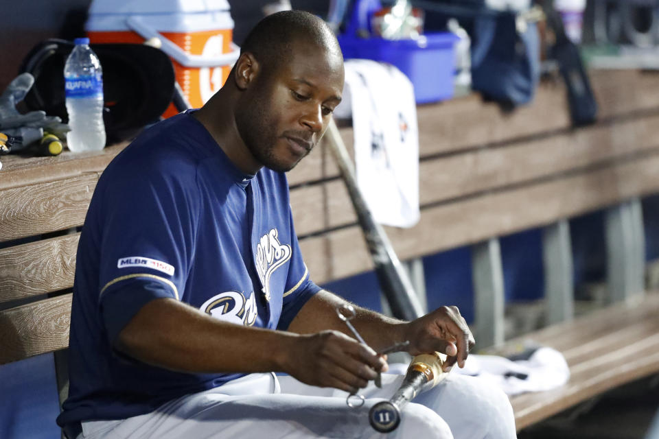 Milwaukee Brewers' Lorenzo Cain takes a pair of scissors to a bat as he sits in the dugout during the fourth inning of a baseball game against the Miami Marlins, Thursday, Sept. 12, 2019, in Miami. (AP Photo/Wilfredo Lee)