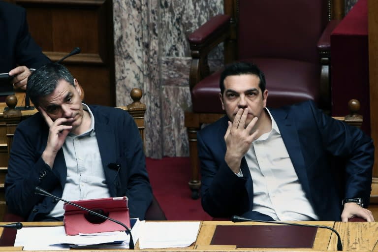 Greek Prime Minister Alexis Tsipras (R) and Finance Minister Euclid Tsakalotos attend a parliamentary session in Athens on adopting fresh cuts and tax hikes