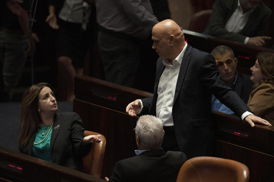 Lawmaker Ghaida Rinawie Zoabi, left, and Minister of Regional Cooperation Issawi Freij, standing, confer during a session of the Knesset, Israel's parliament, ahead of an expected vote on the legal status of Jewish settlers in the occupied West Bank, in Jerusalem, Monday, June 6, 2022. (AP Photo/ Maya Alleruzzo)