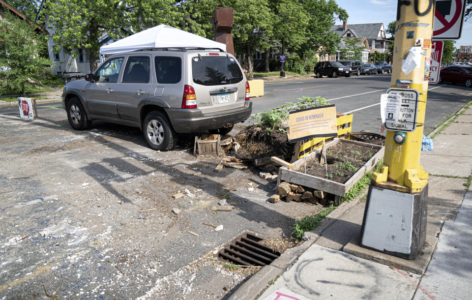 A vehicle and debris remain on the street as crews arrive at George Floyd Square to remove objects used to block traffic on Tuesday, June 8, 2021 in Minneapolis. Workers using front-end loaders and brooms arrived just before 5 a.m. Tuesday and cleared the intersection where Floyd was killed, which is informally known as George Floyd Square. (Glen Stubbe/Star Tribune via AP)