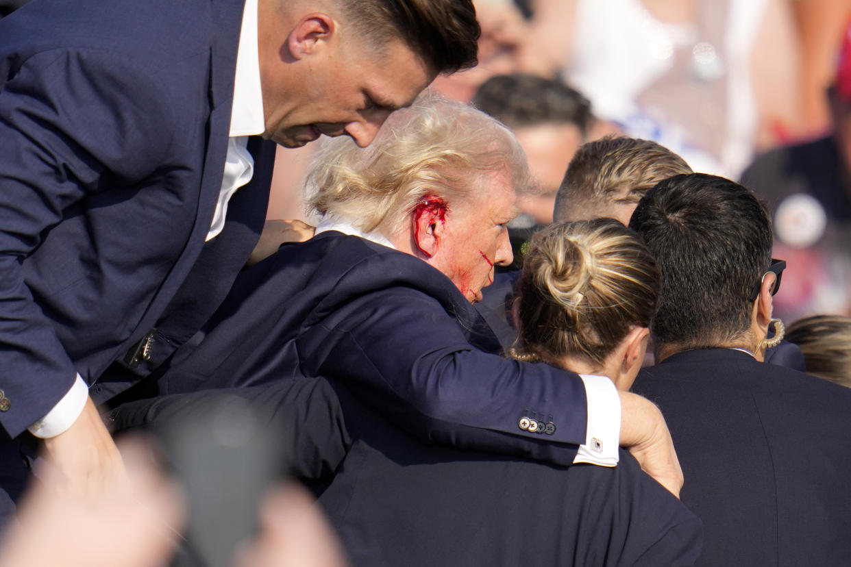  Trump, bleeding at the right ear,  is helped off the stage by Secret Service.