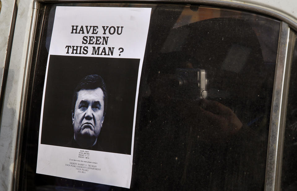 A man takes photos of a wanted notice of fugitive Ukrainian President Victor Yanukovich. (Photo: Yannis Behrakis / Reuters)