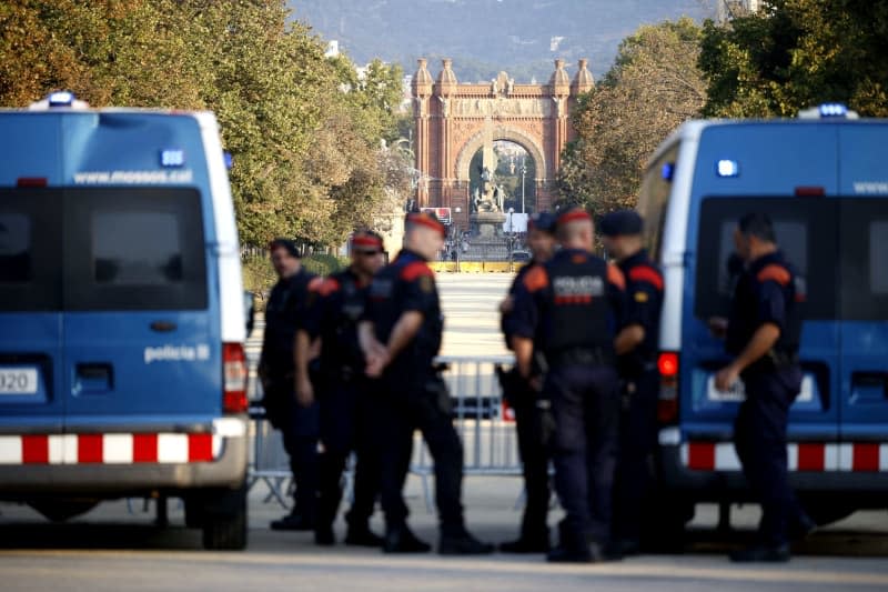 Catalan police officers watch the arrival of pro-independence supporters as hard-line separatists scheduled a welcoming ceremony for Catalonia's exiled separatist leader, Carles Puigdemont, before an investiture vote, in front of Catalonia's Parliament.  Kike Rincón/EUROPA PRESS/dpa