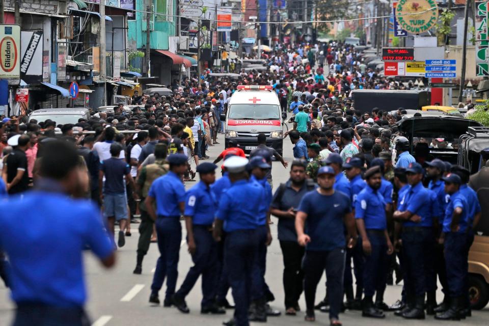 Police officers clear the road as an ambulance drives through carrying the injured in Colombo (AP)