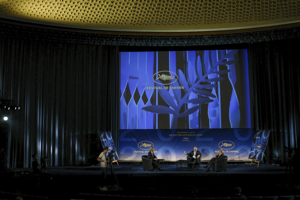 El director del Festival de Cine de Cannes Thierry Fremaux, centro, y el presidente del festival Pierre Lescure, derecha, con el periodista Laurent Weil charlan durante la presentación de la selección oficial del festival 2020 en un cine vacío el miércoles 3 de junio de 2020 en París. El festival de este año se canceló por el brote de coronavirus, pero las películas seleccionadas podrán anunciarse con su “sello de aprobación”. (Serge Arnal, Pool vía AP)