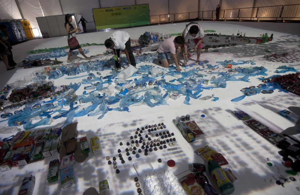 People add waste products to the "Landscape" project by Brazilian artist Vik Muniz that recreates the image of Guanabara Bay in Rio de Janeiro, Brazil, Saturday, June 16, 2012.  Muniz's project recreates city landmarks with recyclable materials donated by the public, who will be able to take their waste to the installation's tent between June 15 and 22, on the sidelines of the UN Conference on Sustainable Development, or Rio+20. (AP Photo/Silvia Izquierdo)