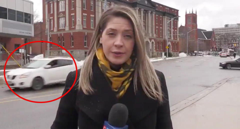 A car drives past reporter Krista Sharpe as a man yells out a vulgar obscenity. 