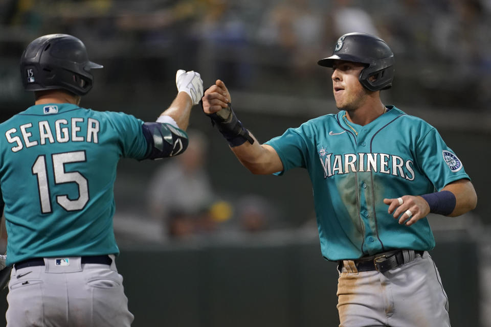 Seattle Mariners' Dylan Moore, right, is congratulated by Kyle Seager after scoring a run against the Oakland Athletics during the third inning of a baseball game in Oakland, Calif., Monday, Sept. 20, 2021. (AP Photo/Jeff Chiu)