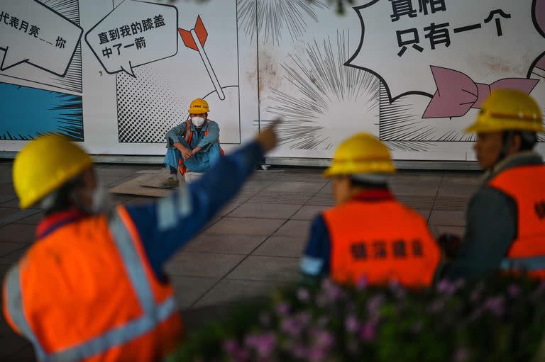 Los trabajadores se toman un descanso en una calle junto a un edificio en renovación en Shanghái, el 12 de octubre de 2022.