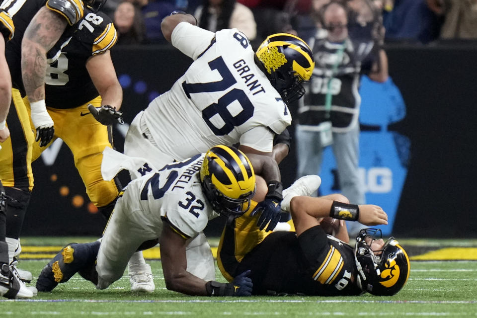 Iowa quarterback Deacon Hill (10) is sacked by Michigan defensive end Jaylen Harrell (32) and defensive lineman Kenneth Grant (78) during the first half of the Big Ten championship NCAA college football game, Saturday, Dec. 2, 2023, in Indianapolis. (AP Photo/AJ Mast)