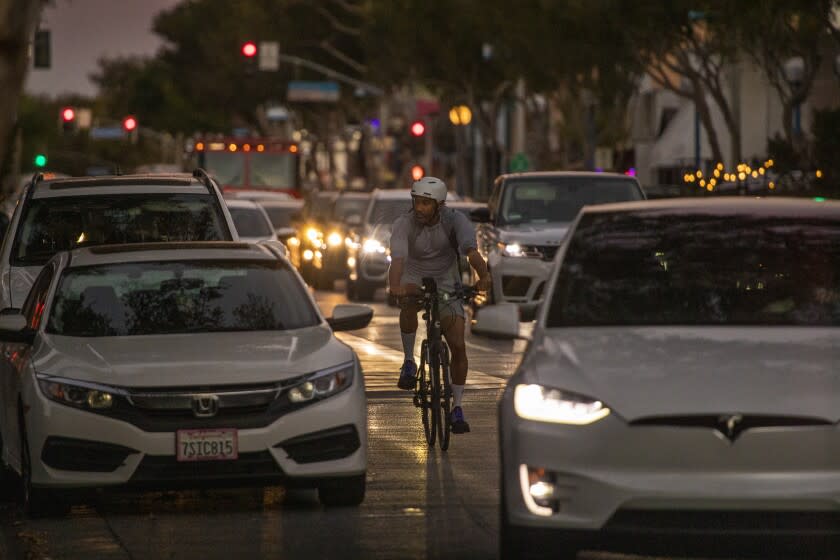 West Hollywood, CA - October 28: A person on a bike rides in traffic along Santa Monica Blvd. in West Hollywood at dusk Thursday, Oct. 28, 2021. (Allen J. Schaben / Los Angeles Times)