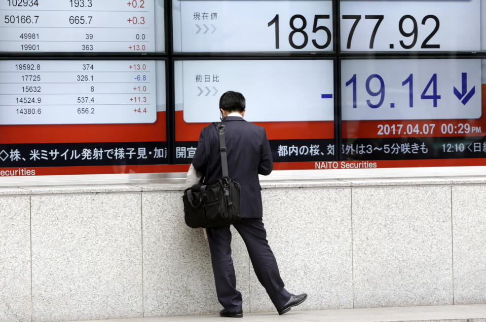 A man stands near an electronic stock board showing morning closing transaction value of Japan's Nikkei 225 index at a securities firm in Tokyo, Friday, April 7, 2017. Asian stock indexes sank Friday as the U.S. fired missiles at a Syrian air base during President Donald Trump's first meeting with China's president, leaving investors on edge over the global outlook. (AP Photo/Eugene Hoshiko)