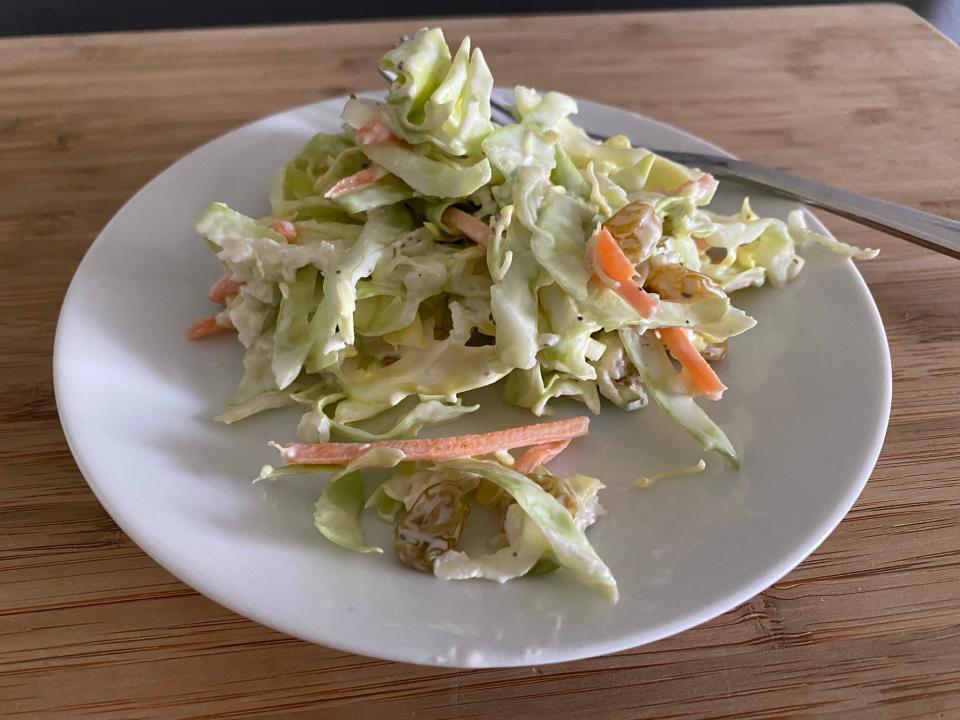 closeup shot of sunny anderson's apple and raisin coleslaw on a white plate