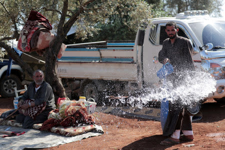 FILE PHOTO: Ahmen al-Hussein, 32, a displaced Syrian pours water in an olive grove in the town of Atmeh, Idlib province, Syria May 19, 2019. REUTERS/Khalil Ashawi