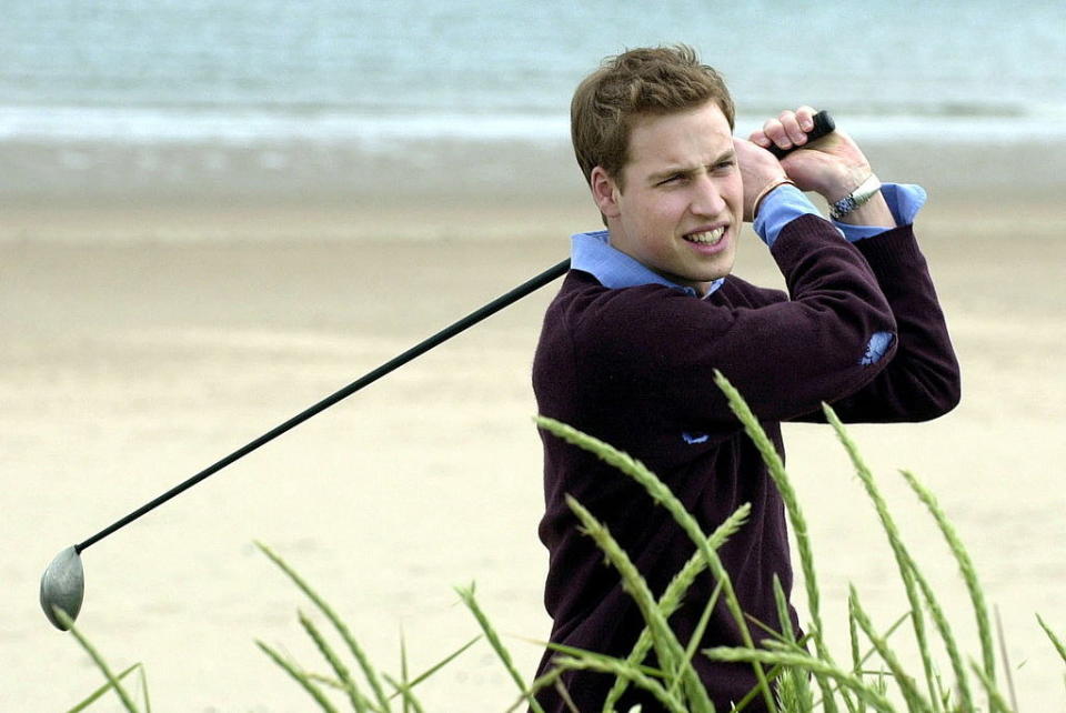 He's looking in the distance for the ball and smiling, the iron over his shoulder, with the sand and sea behind him