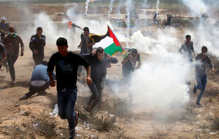 Palestinians run from tear gas fired by Israeli troops during clashes at the Israel-Gaza border at a protest demanding the right to return to their homeland, east of Gaza City April 6, 2018. REUTERS/Mohammed Salem