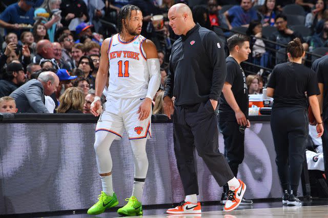 <p>Michael Gonzales/NBAE via Getty</p> Assistant Coach Rick Brunson and Jalen Brunson #11 of the New York Knicks talk during the game against the San Antonio Spurs on March 29, 2024 at the Frost Bank Center in San Antonio, Texas during