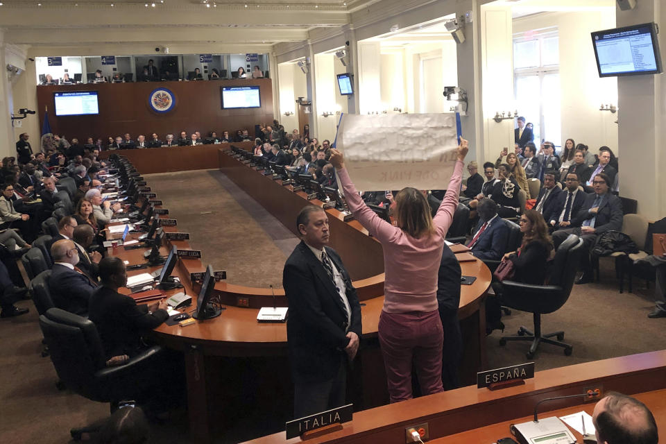 Activist Medea Benjamin with the group Code Pink, standing center, heckles remarks by Secretary of State Mike Pompeo during an extraordinary session about the crisis in Venezuela held by the Organization of American States, Thursday Jan. 24, 2019 in Washington. (AP Photo/Luis Alonso Lugo)