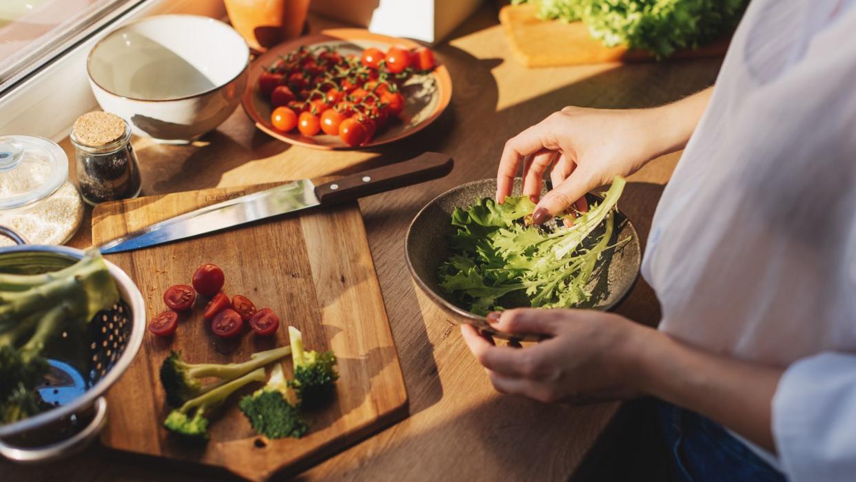  Women preparing salad with some of the best foods to have in the evening, including leafy green vegetables. 