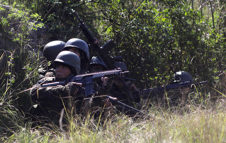 Brazilian Army soldiers take cover during a shootout with drug gangs during an operation in Alemao slums complex in Rio de Janeiro, Brazil August 20, 2018. REUTERS/Ricardo Moraes