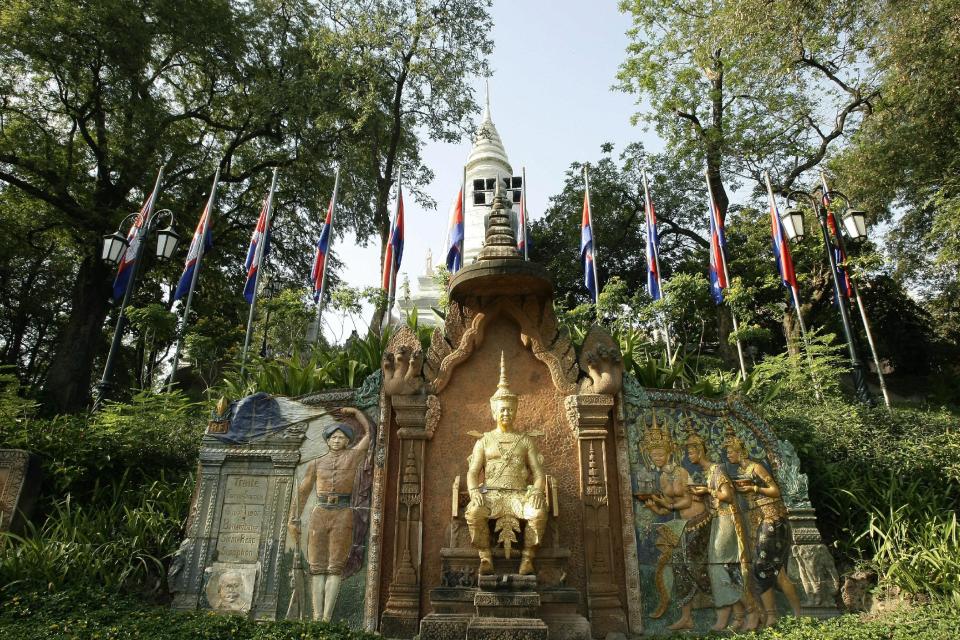 In this photo taken, Feb. 25, 2013, the statue of former King Sisowath, center, is displayed at Wat Phnom, in Phnom Penh, Cambodia. With a pricetag of a dollar, admission to the centuries-old hilltop temple of Wat Phnom isn't quite free. Nor are the elephant rides that are offered on site. But a free and carefree stroll along the bucolic grounds is a reward in and of itself. Sculpted into the hillside leading to the temple's entrance is a functioning topiary clock, whereas the gigantic sculpture of a Naga, or sea snake, provides yet another photo op. (AP Photo/Heng Sinith)