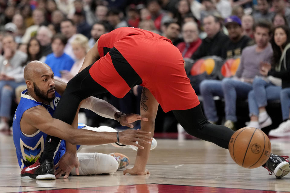 Milwaukee Bucks guard Jevon Carter (5) passes around Toronto Raptors forward Ron Harper Jr. (8) as they scramble around the ball during first half of an NBA basketball game in Toronto, Sunday, April 9, 2023. (Frank Gunn/The Canadian Press via AP)