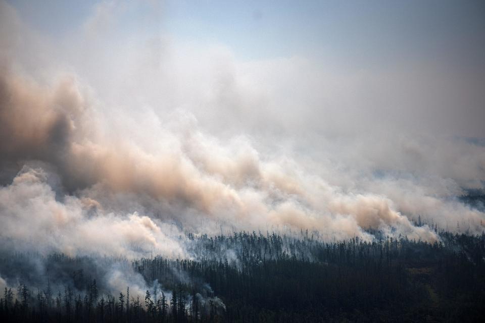 This photo, taken from an airplane on July 27, 2021, shows the smoke rising from a forest fire outside the village of Berdigestyakh, in the republic of Sakha, Siberia.  / Credit: DIMITAR DILKOFF/AFP via Getty Images