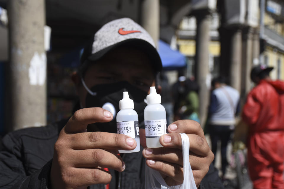 A man shows bottles of chlorine dioxide he purchased at a pharmacy in Cochabamba, Bolivia, Friday, July 17, 2020. Long lines form every morning in Cochabamba, one of the Bolivian cities hardest hit by the new coronavirus pandemic, as people wait to buy small bottles of chlorine dioxide, a toxic bleaching agent that has been falsely touted as a cure for COVID-19 and myriad other diseases. (AP Photo/Dico Solis)