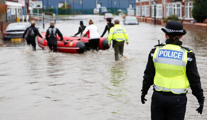 A police officer looks at a rescue boat on a flooded street in Bentley