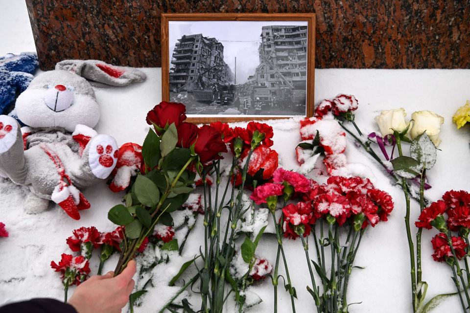 A person lays flowers in memory of those killed in the weekend strike in Ukraine at the monument to famous Ukrainian poet Lesya Ukrainka in Moscow on January 17, 2023.